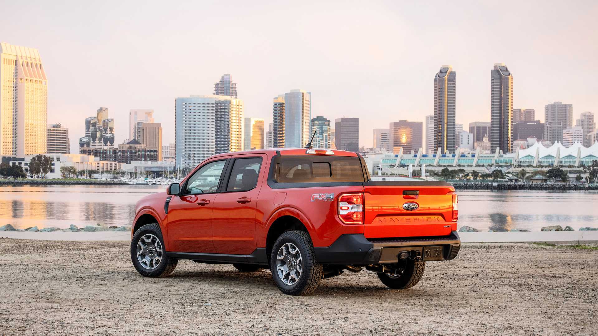 an orange 2022 ford maverick stanced up in front of a city skyline.